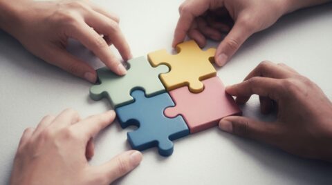 Vier Hände haben gemeinsam ein Puzzle zusammengesetzt